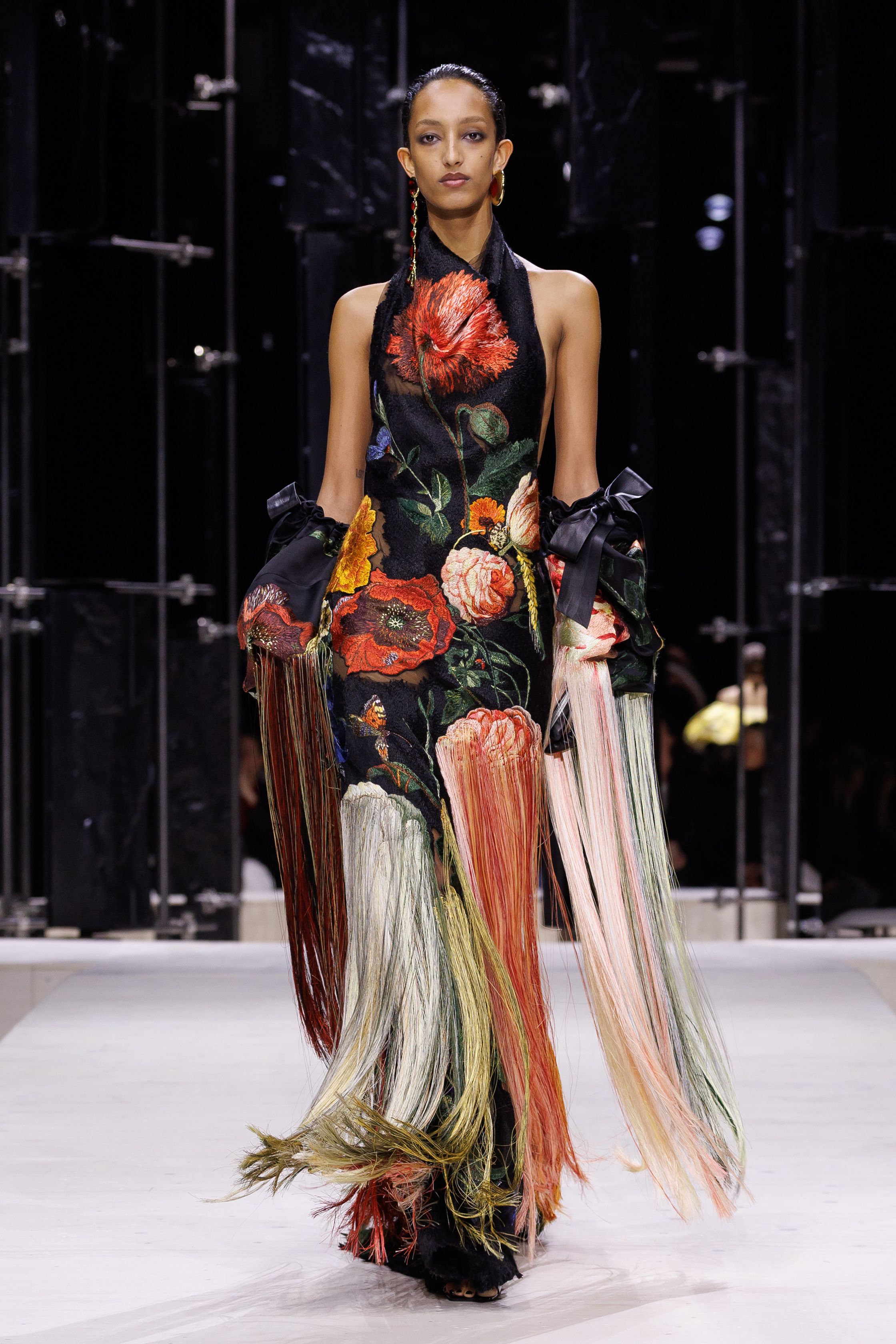 Givenchy 2026秋冬在现代建筑空间中呈现一场充满戏剧性的时装叙事：雕塑式西装、亮色斗篷、结构礼服与夸张装饰共同构建品牌标志性的高级时装气质。蓝色、红色与黄色的高饱和色彩与黑白经典形成鲜明对比，服装通过立体剪裁与夸张廓形展现出强烈视觉张力。整场系列在优雅与戏剧之间取得平衡，展现现代高级时装的力量-顽石频道趋势研究
